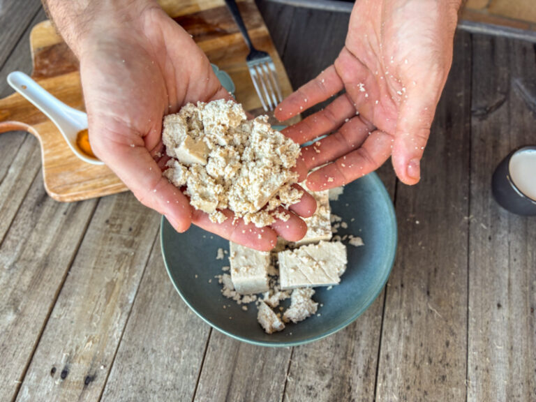 Image of PT Matt's hands halfway through crumbling hard tofu into a bowl.